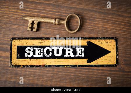 SECURE Concept. Direction arrow with text and golden key on wood texture background. Stock Photo