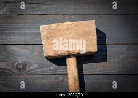 Old wooden carpenter's hammer on dark wood texture background. Stock Photo