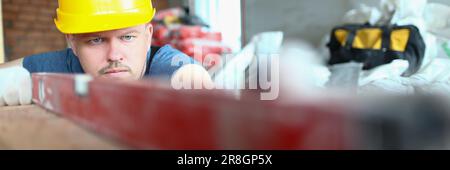 Bricklayer checks evenness of brick wall, brick foundation using spirit level Stock Photo