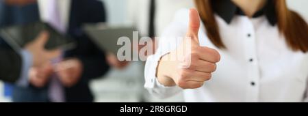 Businessman holds thumbs up in background are business partners Stock Photo