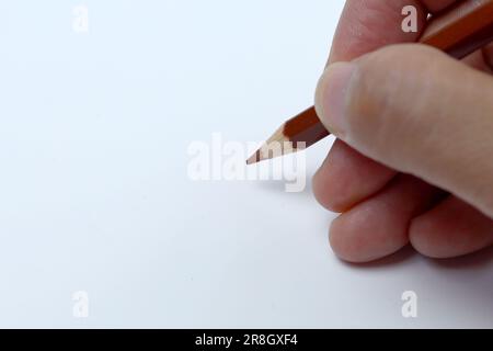The right hand is drawing with pencil color. Isolated on white background. Stock Photo