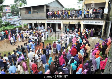Sylhet, Bangladesh. 21st June 2023.  Thousands of voters came to the polling station of Rashidiya Dakhil Madrasa, word number 38, which was newly added to Sylhet City Corporation. People thronged the polling stations spontaneously but the slowness of EVMs disappointed them. Meanwhile, Ansar members are standing in line and showing how to vote at EVM machines. Stock Photo