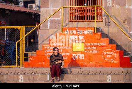 Varanasi, Uttar Pradesh, India - March 05 2023: Portrait of foreigner woman sitting on stairs of temple at assi ghat during morning. Stock Photo