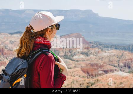 Woman with a backpack looking on the panorama of Bryce canyon in Utah. Summer hiking. Stock Photo