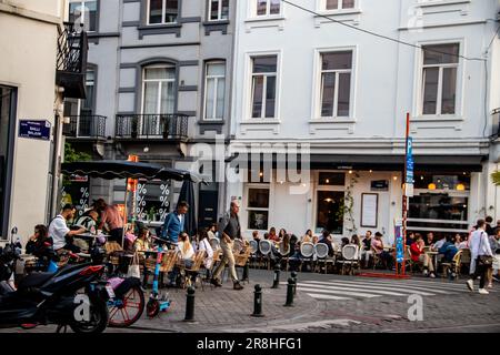 Brussels streets buzz with lively energy as people stroll along, savoring the atmosphere. Charming street bars dot the sidewalks and street bars Stock Photo
