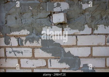A close-up view of a brick wall, messily fixed with gray cement Stock Photo