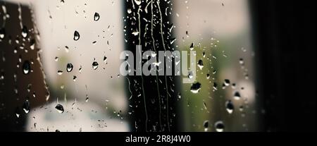 Rain drop on window glass of coffee shop and blurry city life background. Rainy season and blurry people city day life or bokeh night lights outside w Stock Photo