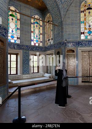 Tourist inside an elegant room in the Topkapi Palace with blue and white tiles, stained glass windows, Fatih district, Istanbul, Turkey Stock Photo