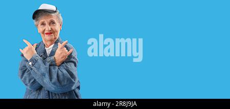 Stylish senior woman showing devil horns gesture on light blue background with space for text Stock Photo