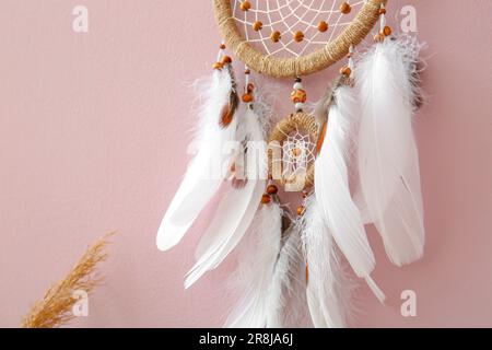 Dream catcher hanging on pink wall, closeup Stock Photo