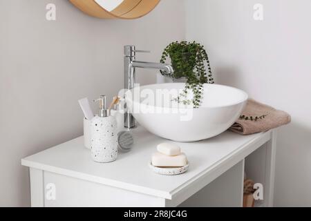 Sink bowl, soap bars, dispensers and bath accessories on table in bathroom Stock Photo