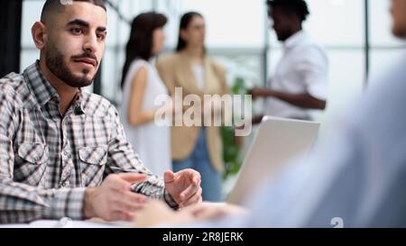 Young adult caucasian male, hiring manager, sits at a desk in a modern office Stock Photo