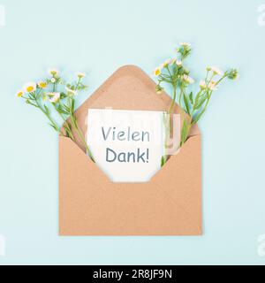 Thank you card in an envelope surrounded by flowers, being thankful, support, help and charity concept, positive attitude, german language Stock Photo