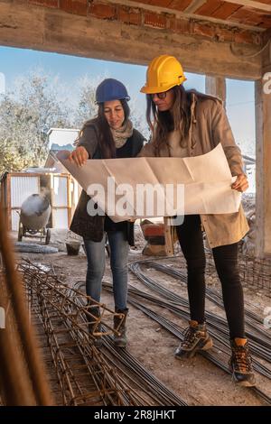 Architecture, Women with hard hat, working on the construction of a building working in a team and blueprint reading. Blueprint, architecture and wome Stock Photo