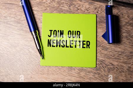 Phrase Join our newsletters written on notebook with office tools on wooden table. Motivational concept. Stock Photo