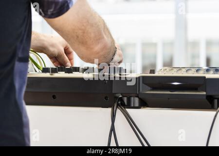 The arms of a dj playing with music on his mixing desk Stock Photo