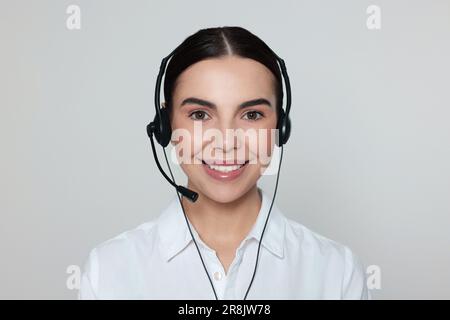 Hotline operator with modern headset on light grey background. Customer support Stock Photo