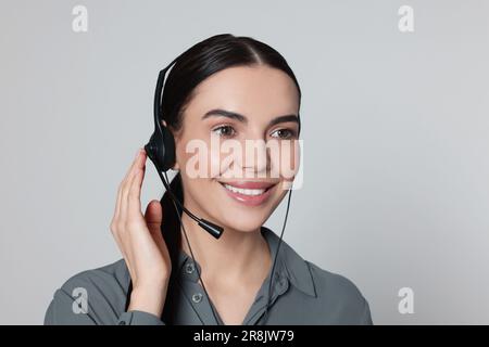 Hotline operator with modern headset on light grey background. Customer support Stock Photo