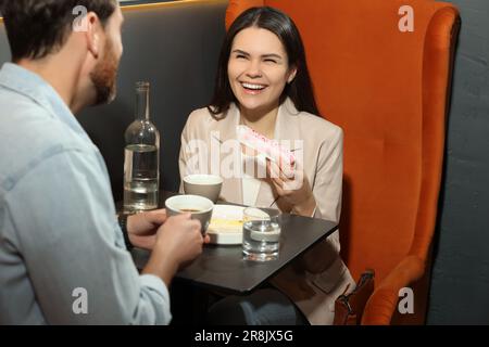 Couple with coffee and eclairs spending time together in cafe Stock Photo