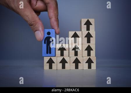 Hand holding wooden cube with person icon and upward arrow. Personal development, personal and career growth, success, progress, motivation and potent Stock Photo