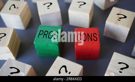 Selective focus image of wooden blocks with question mark, text PROS and CONS. Stock Photo