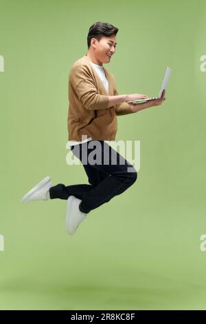 Profile photo of sporty active guy jump hold netbook run work isolated green color background Stock Photo