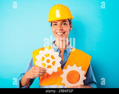 Engineer woman joins pieces of gears as concept of partnership and integration Stock Photo