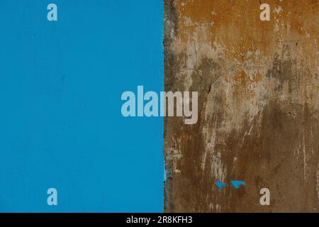 old concrete with brown plaster wall partially painted in blue, texture and background Stock Photo