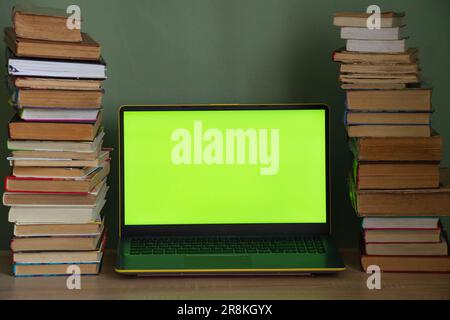 laptop green screen and a stack of books on the table Stock Photo