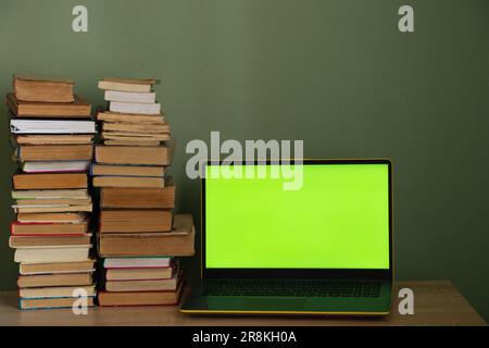 laptop green screen and a stack of books on the table Stock Photo