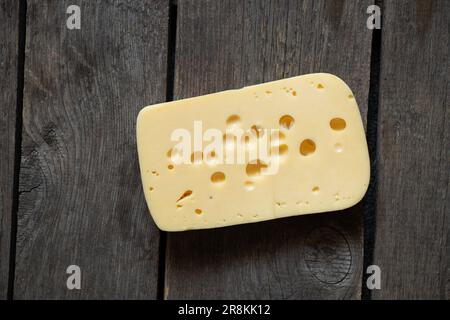 a piece of hard cheese on a wooden table close-up Stock Photo