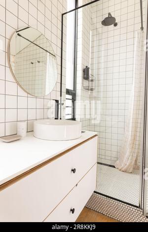 View of bright modern bathroom interior with white tiles and glass shower cabin Stock Photo