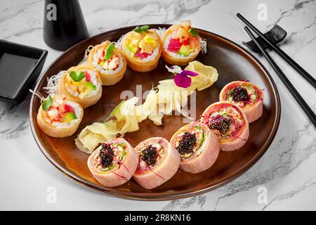 Two types of sushi rolls in mamenori served on plate with ginger Stock Photo