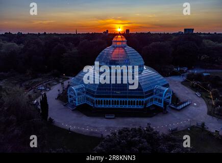 The sun sets on the evening of the summer solstice behind the palm house in Sefton Park, Liverpool, Merseyside. Stock Photo