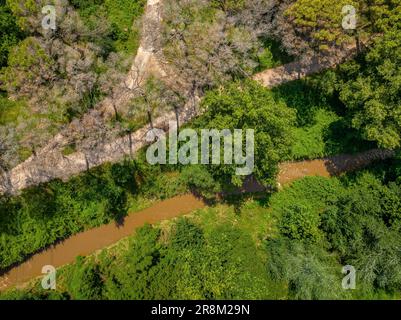Aerial view of the Tenes river as it passes through Santa Eulàlia de Ronçana, surrounded by forest and green fields in spring (Barcelona, Spain) Stock Photo
