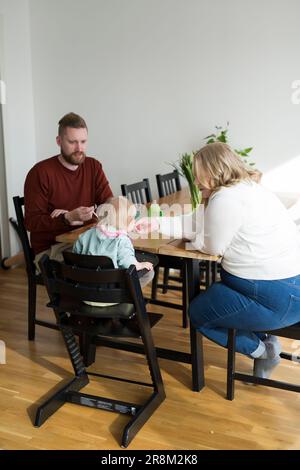 Parents with Toddler with down syndrome sitting at table Stock Photo