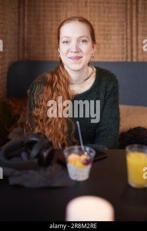 Portrait of smiling young redheaded woman in cafe Stock Photo