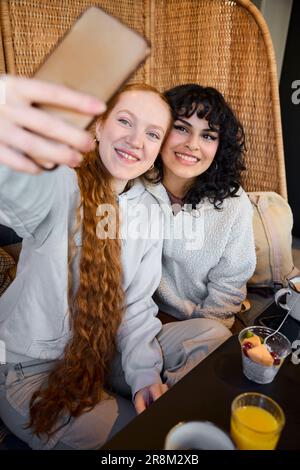 Smiling young women taking selfie in cafe Stock Photo