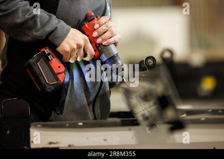 Woman using drilling machine in factory Stock Photo