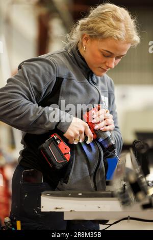 Woman using drilling machine in factory Stock Photo