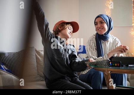 Mother wearing hijab helping son doing homework Stock Photo