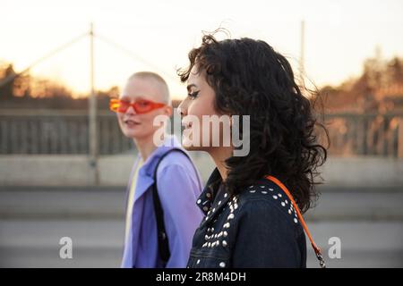 Side view of smiling young woman, female friend in background Stock Photo