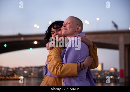 Happy young female friends or gay couple hugging each other Stock Photo