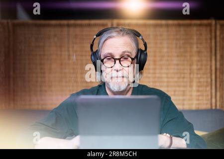 Senior man with headphones using tablet Stock Photo