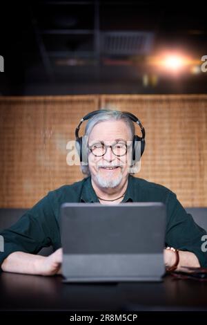 Smiling senior man with headphones using tablet Stock Photo
