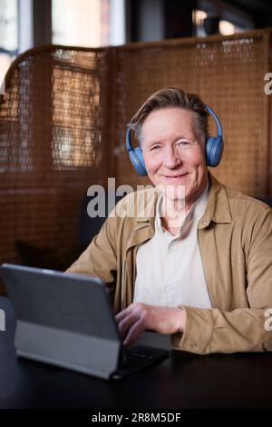 Portrait of senior man with headphones using tablet Stock Photo