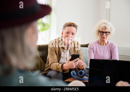 Smiling senior man and woman sitting in living room and using laptop Stock Photo
