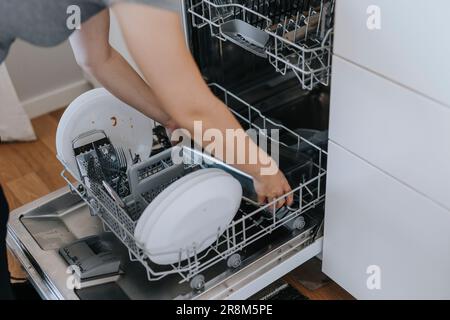 Woman putting dirty dishes in dishwasher Stock Photo