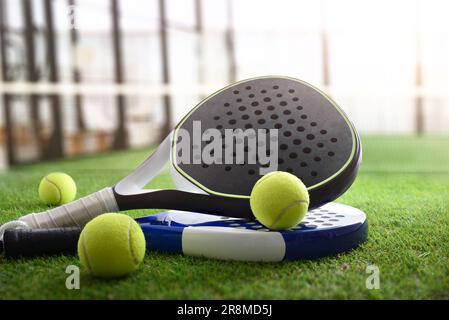Padel rackets and balls on artificial grass floor in outdoor court. Front view. Stock Photo