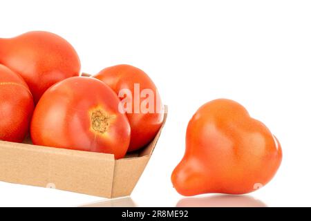 Several juicy red tomatoes on a paper tray, macro, isolated on white background. Stock Photo